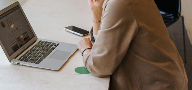 woman in brown coat using macbook air by Daria Pimkina courtesy of Unsplash.