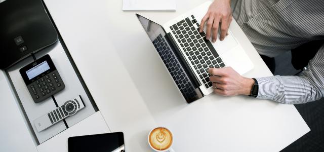 person using laptop on white wooden table by Tyler Franta courtesy of Unsplash.